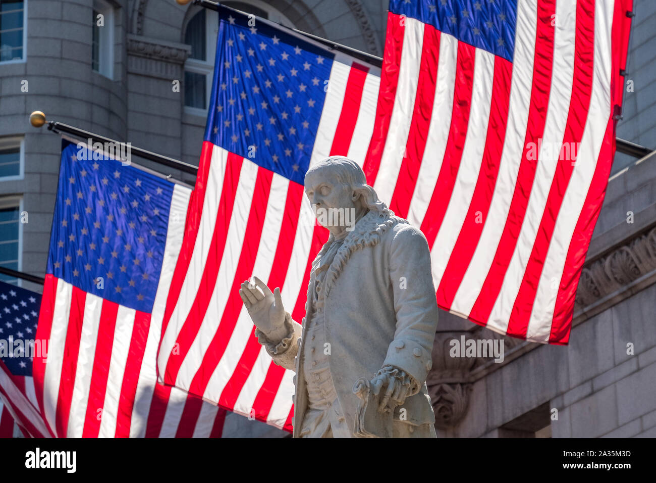 Statue of Benjamin Franklin backed by US Flags, Penn Quarter, Washington DC, USA Stock Photo