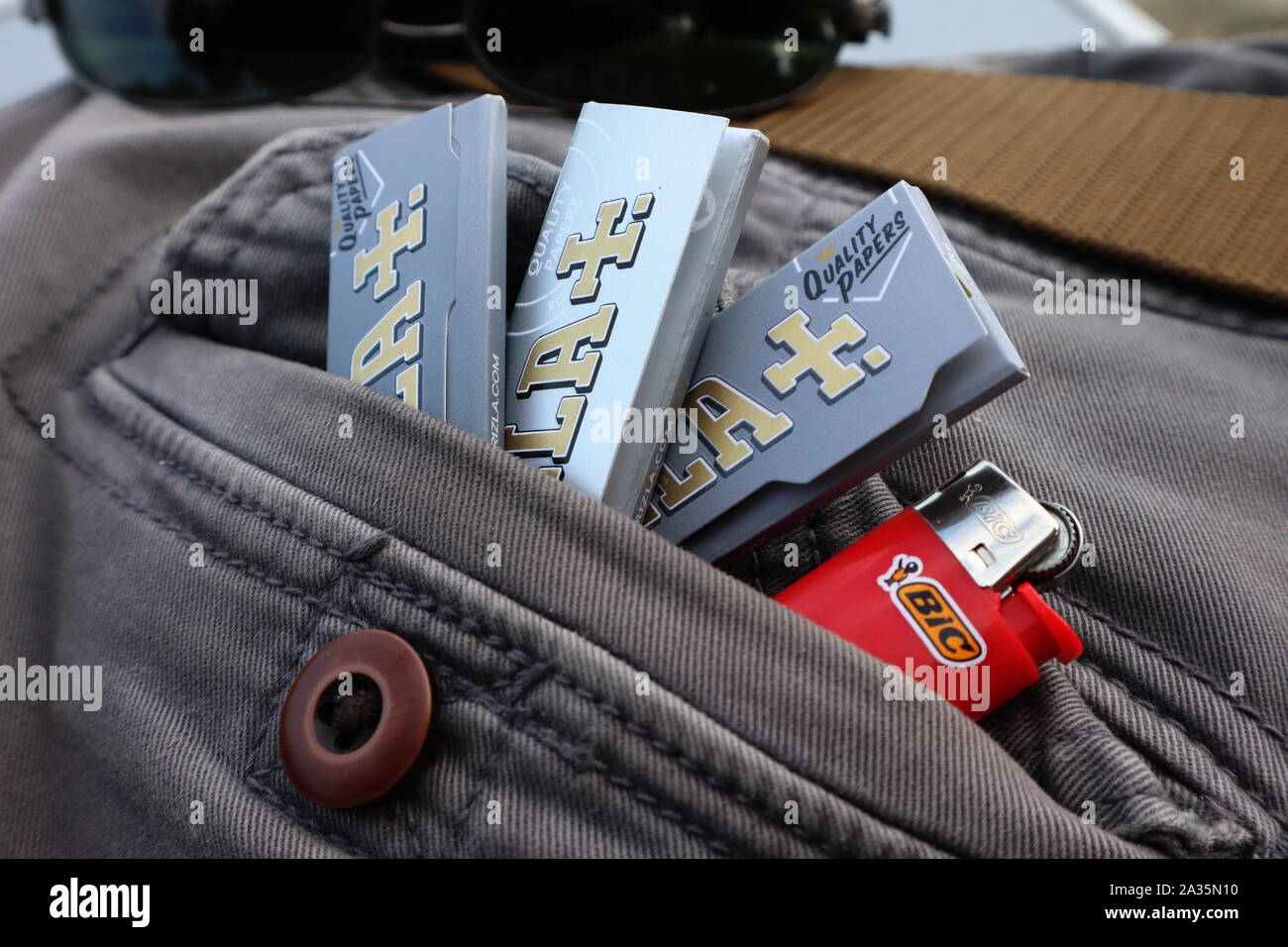 Packets of Rizla cigarette rolling paper with Bic mini lighter in back pocket of grey denim pants Stock Photo