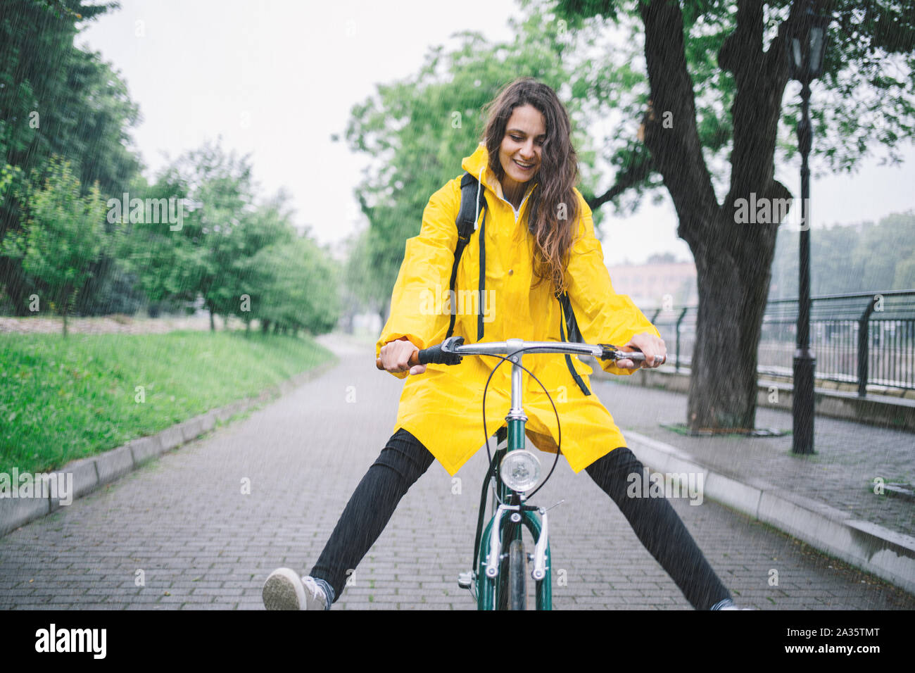 Bicycle ride in the rain. Young woman with raincoat Stock Photo Alamy