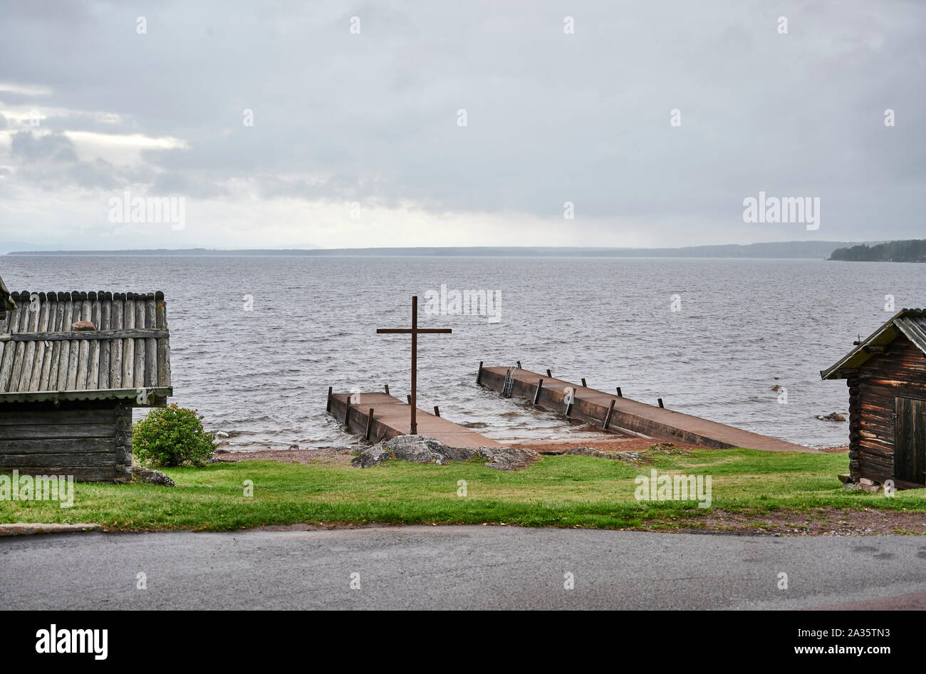 Vid Siljans strand nedanför Rättviks kyrka finns detta kristna kors för att välkomna kyrkroddarna till bryggan inför högmässan. Stock Photo