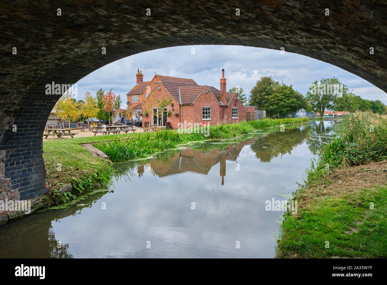 The Dirty Duck public house or pub next to Grantham Canal at Woolsthorpe by Belvoir in Lincolnshire framed by the arch of a towpath bridge Stock Photo