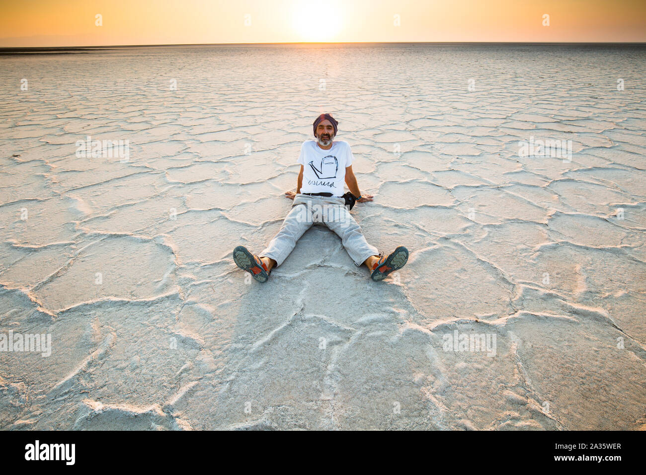 Man seated on a salt lake. Stock Photo