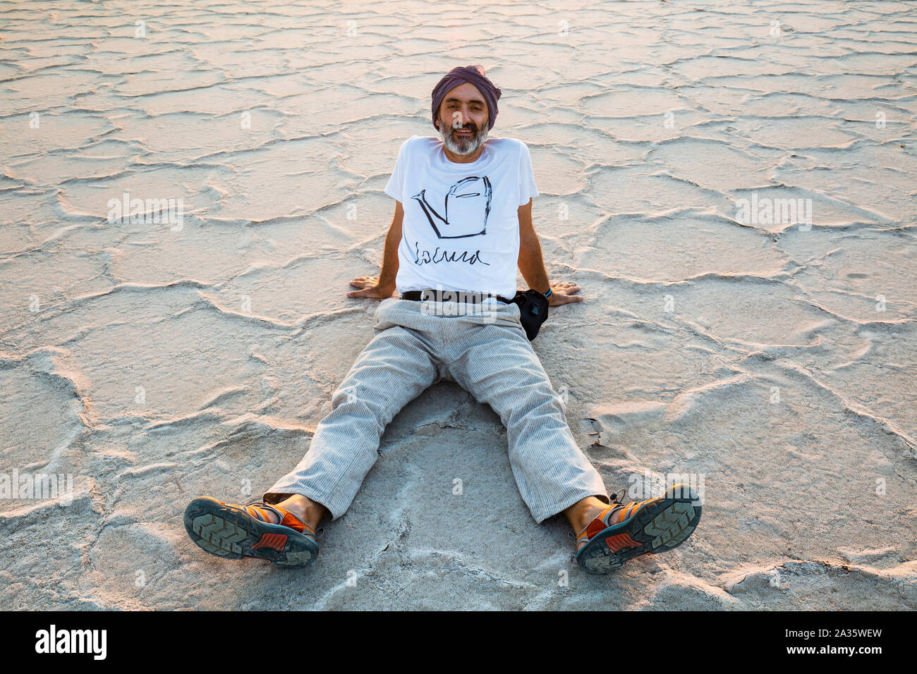Man seated on a salt lake. Stock Photo