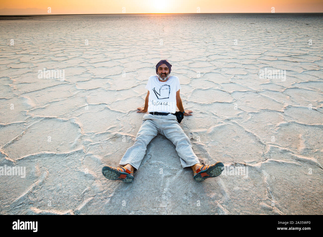 Man seated on a salt lake. Stock Photo