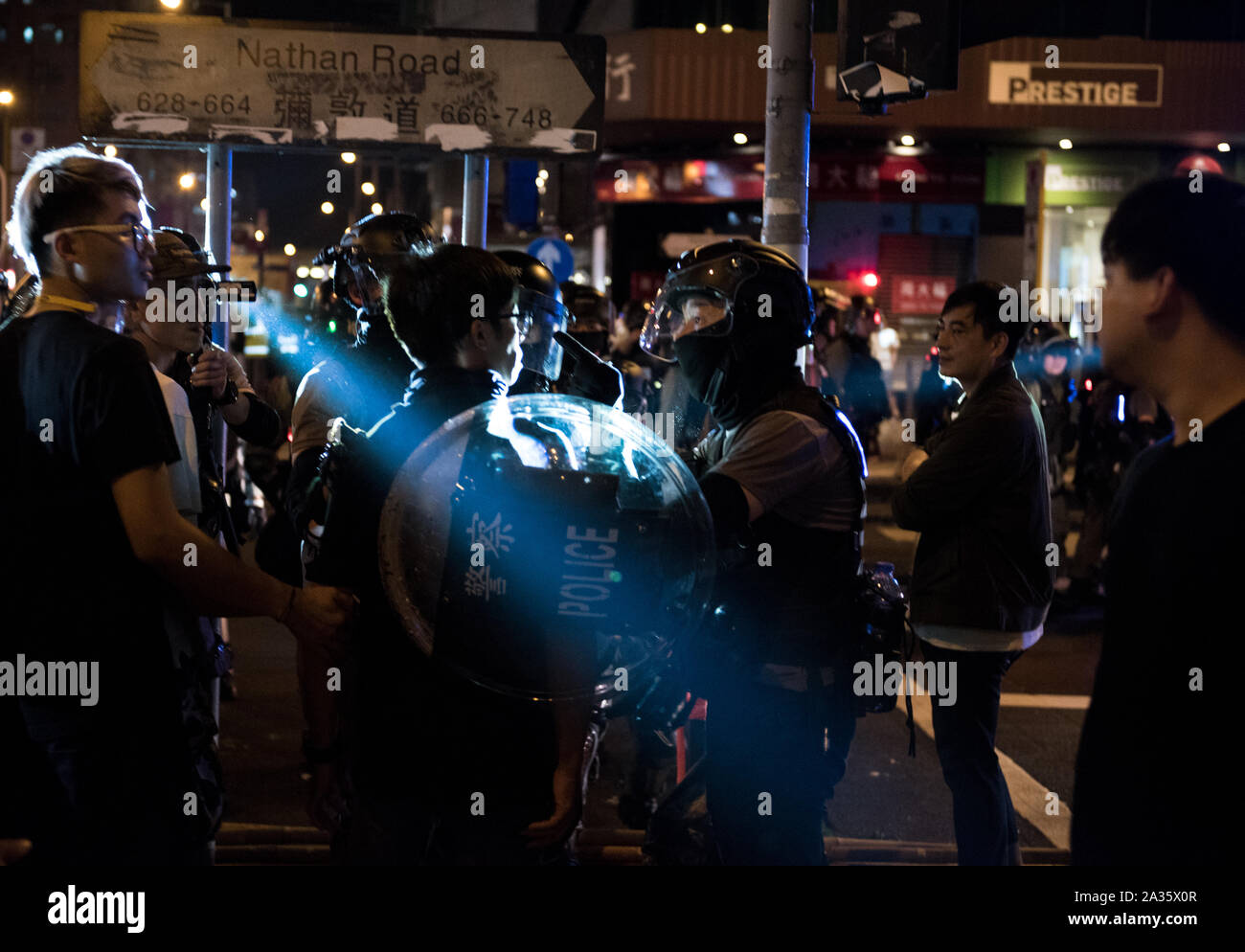A police officer interrogates a man on the sidewalk.Protesters participated in spontaneous rallies and marches all across Hong Kong in response to the recent anti-mask law passed the previous day. Marches and rallies during the day were largely uninterrupted by police, although riot police conducted several dispersal operations at night. Stock Photo