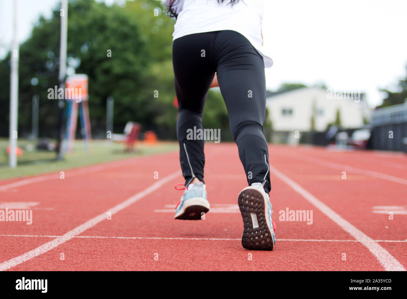 A high school girl practices sprinting straight in lane at track and