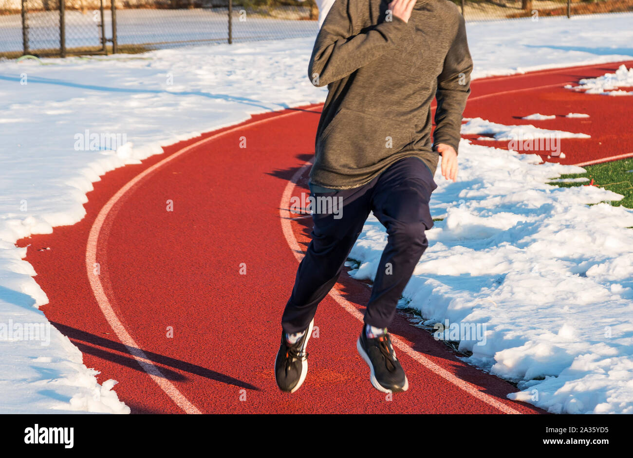 A high school boy is running on a track in lane one with the rest of