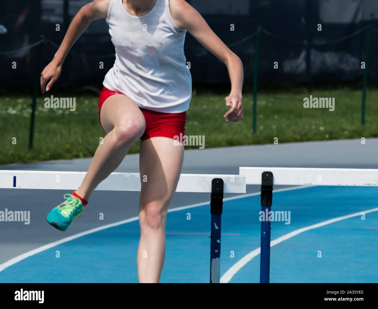 A high school girl is running over hurdles during a 400 meter hurdle