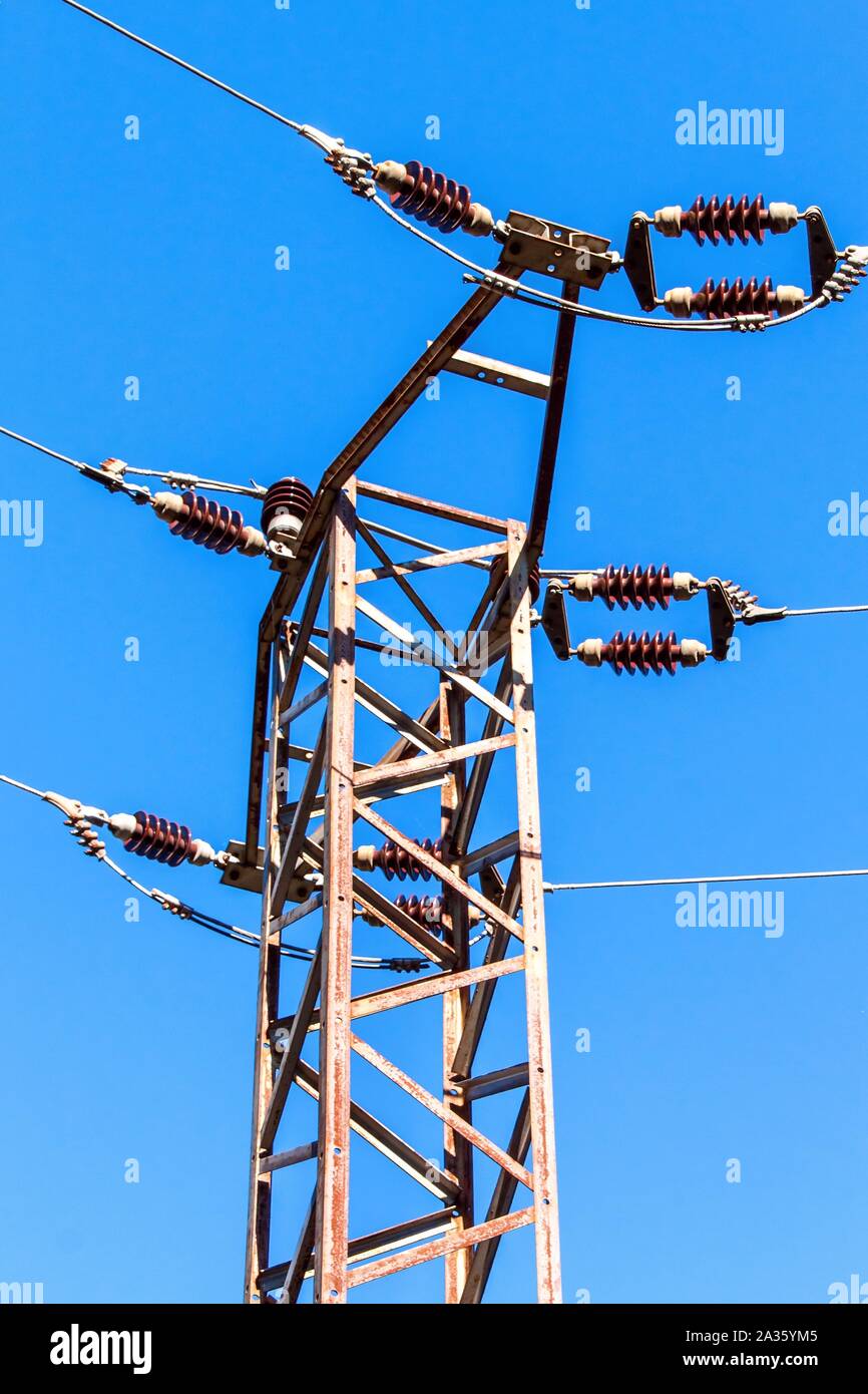 Distribution of electricity. Power pillar against blue sky. Ceramic insulator. Electrical energy. Stock Photo