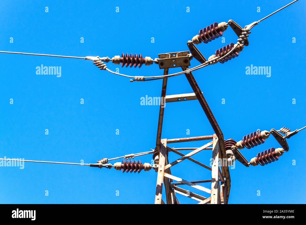 Distribution of electricity. Power pillar against blue sky. Ceramic insulator. Electrical energy. Stock Photo