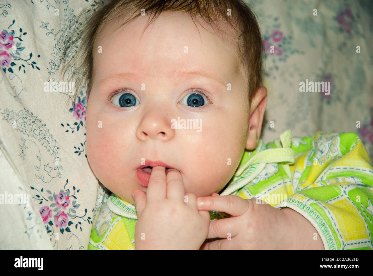 Adorable two month old baby girl lying on the pillow and looking into