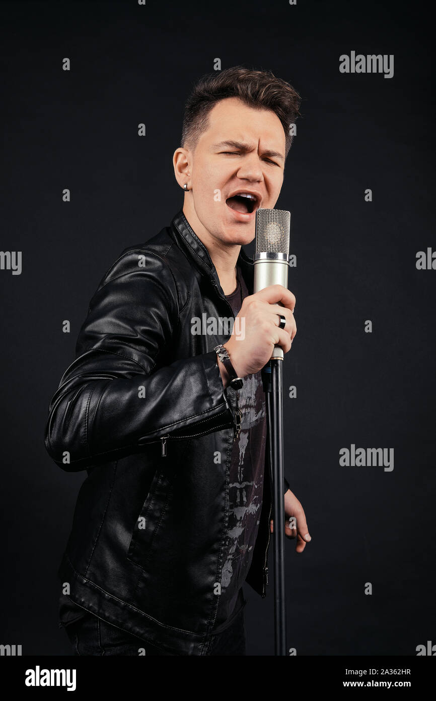 Low key portrait of man singing and holding microphone Stock Photo