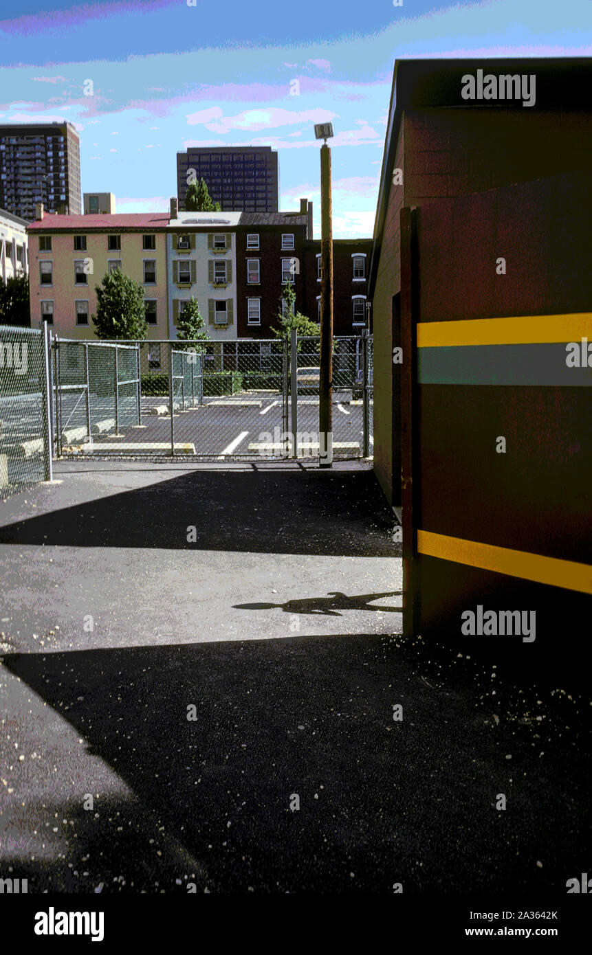 Dark shadow appear around corner. Playground, parking area near high rise apartments and row houses. Stock Photo