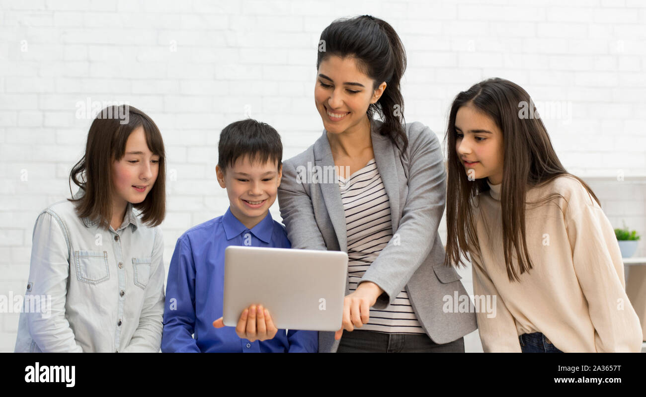 Teacher and kids looking on tablet computer during break Stock Photo
