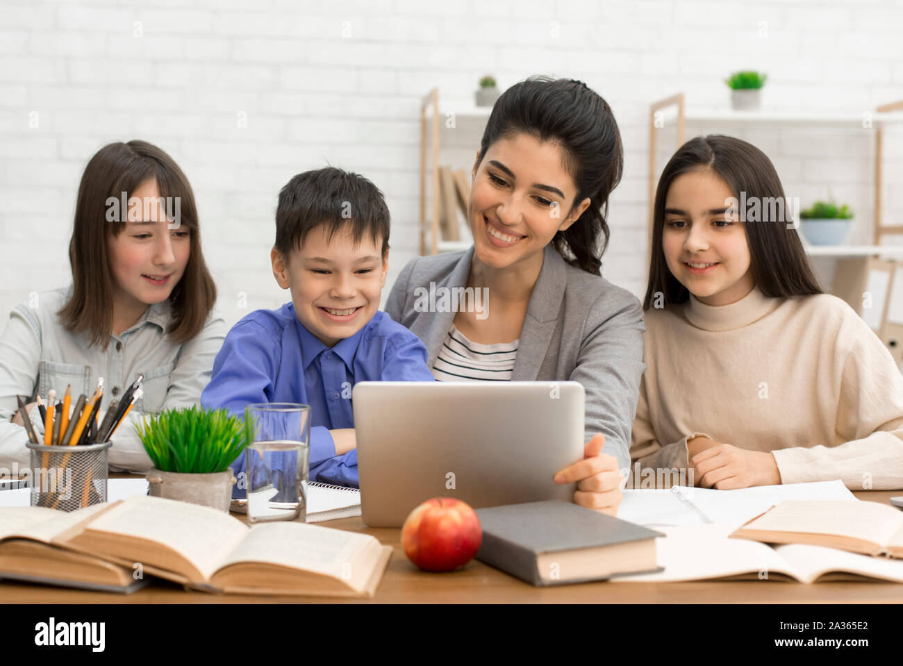 Pupils and teacher watching interesting videos on tablet Stock Photo