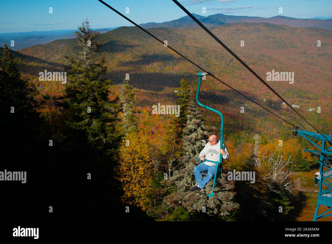 A man rides the single chair at the MadRiver Glen ski area in Fayston, Vermont, USA 10/51019 during green and gold weekend as peak foliage hits much o Stock Photo