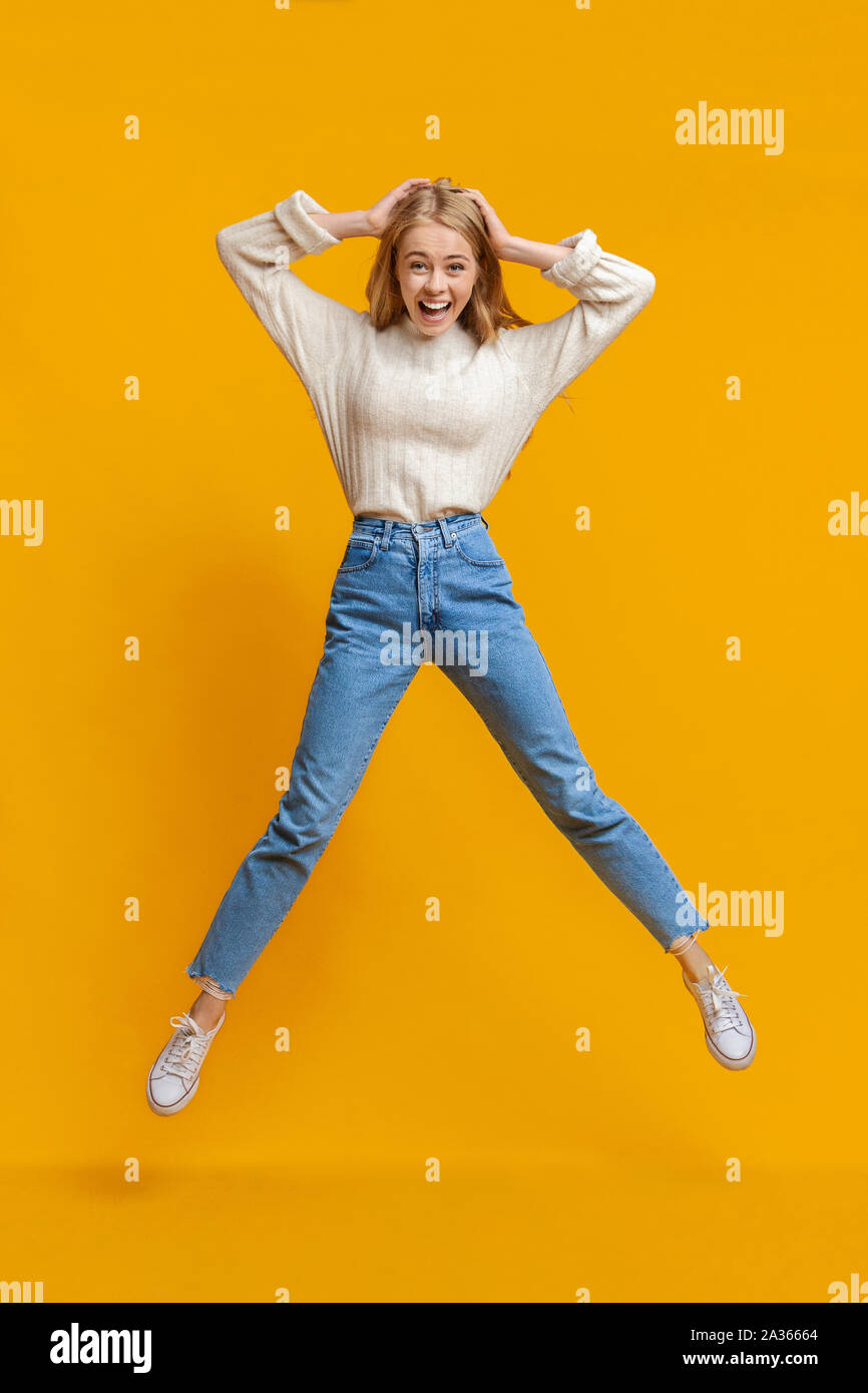 Excited girl jumping in air with hands on head Stock Photo - Alamy