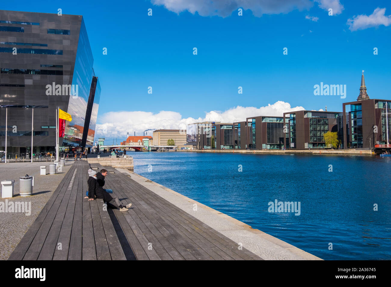 Copenhagen, Denmark - May 04, 2019: People relax on one of the waterfront near the Black Diamond, the Copenhagen Royal Library Stock Photo