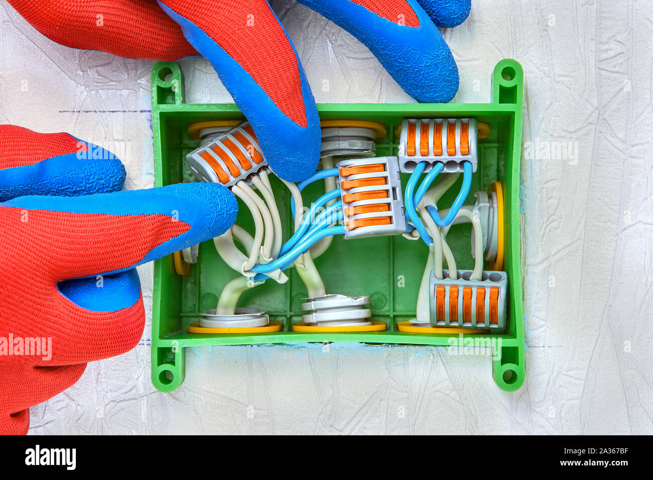 Electrical work. An electrical terminal block with push lever, used to connect and extend the wires inside a rectangular plastic junction box. Distrib Stock Photo