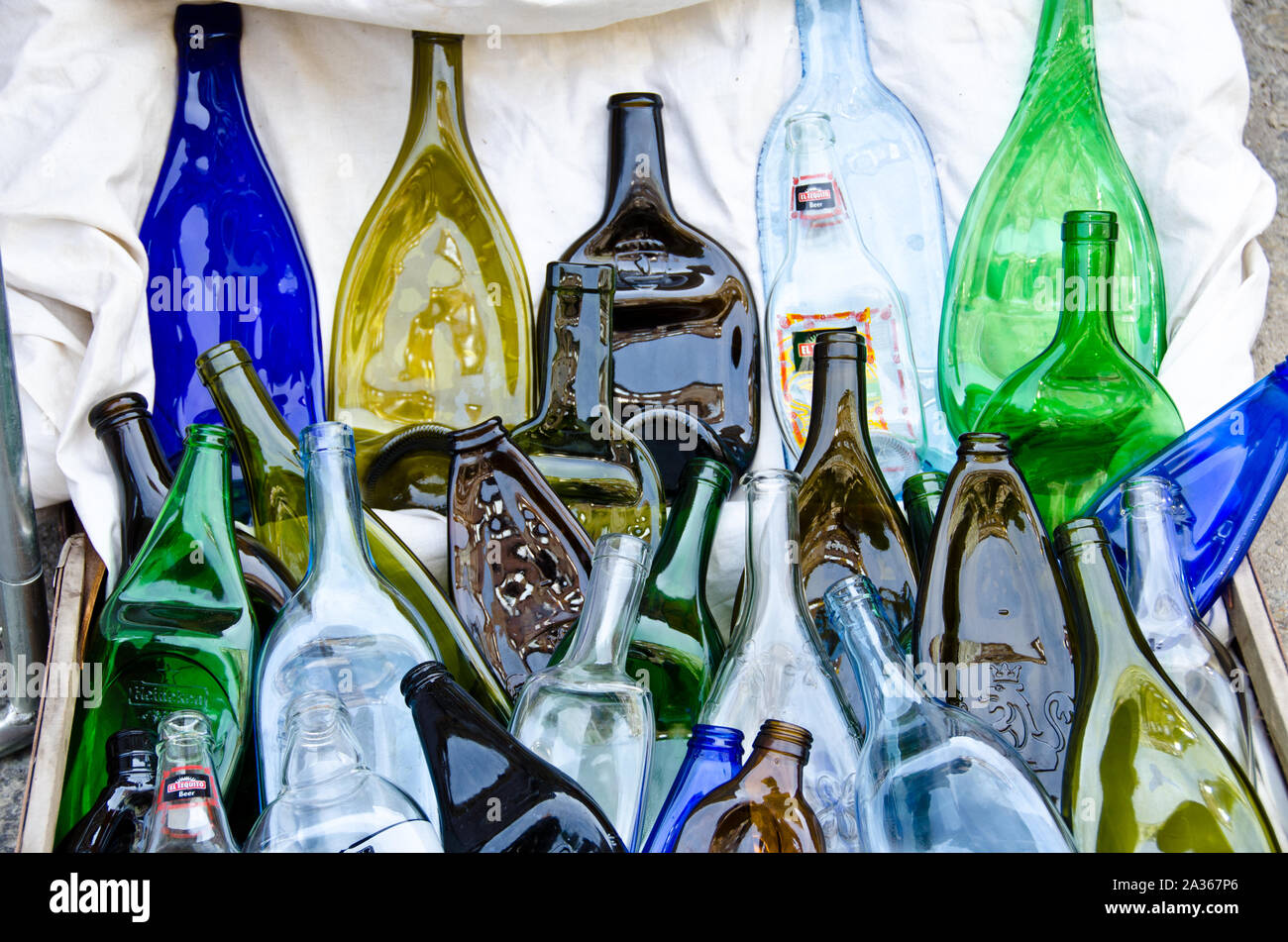 Many coloured, compressed, flat bottles from glass, laying on the