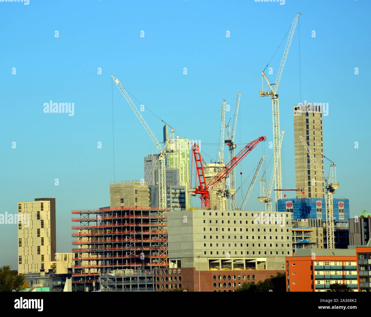 Construction of high rise buildings with tower cranes in central Manchester, United Kingdom, against a blue sky Stock Photo