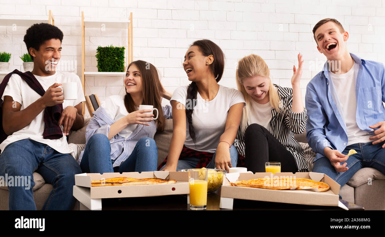 Happy teens eating pizza at home party and chatting Stock Photo