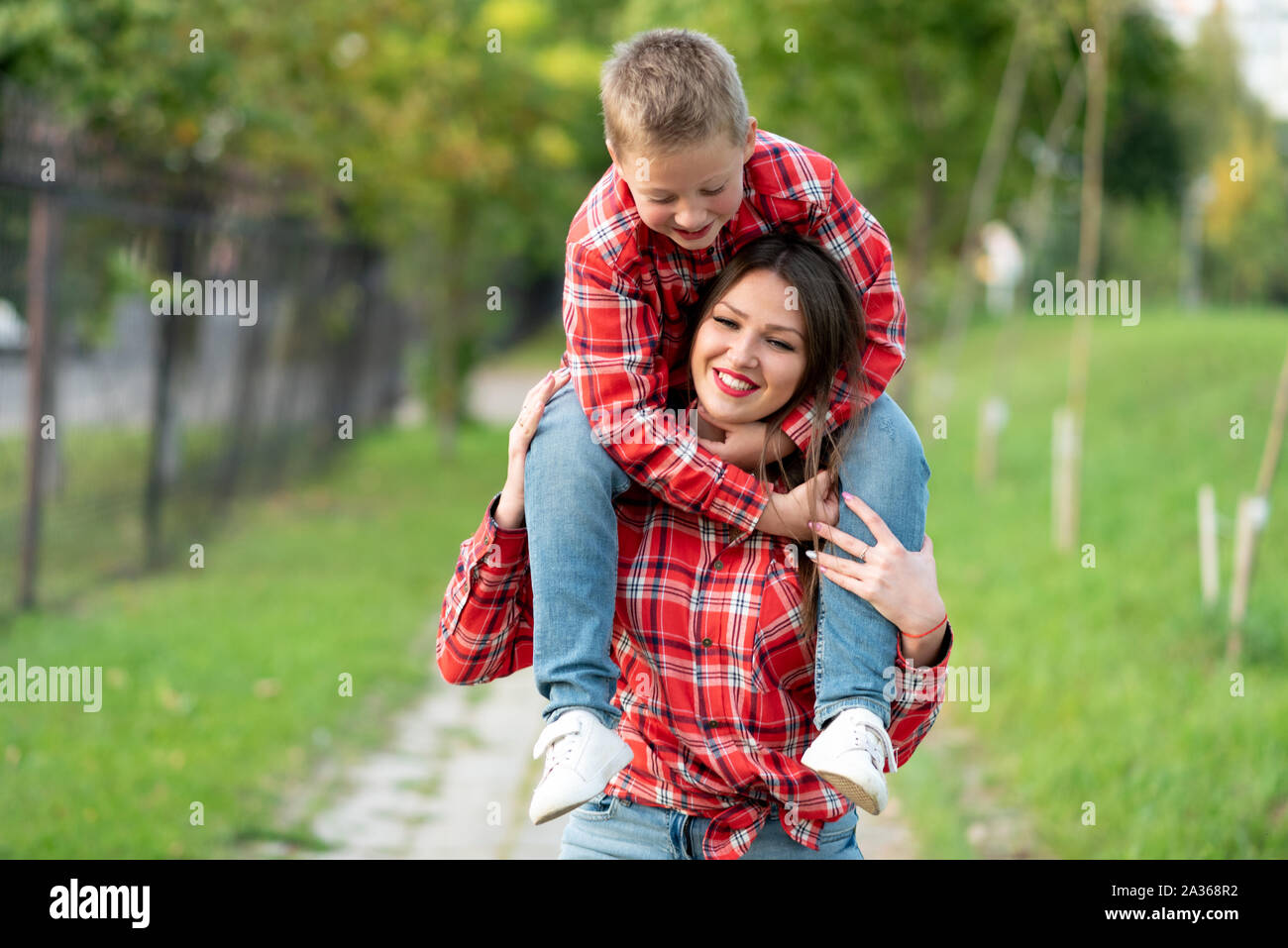Mom, smiling, carries a son on his shoulders. Stock Photo