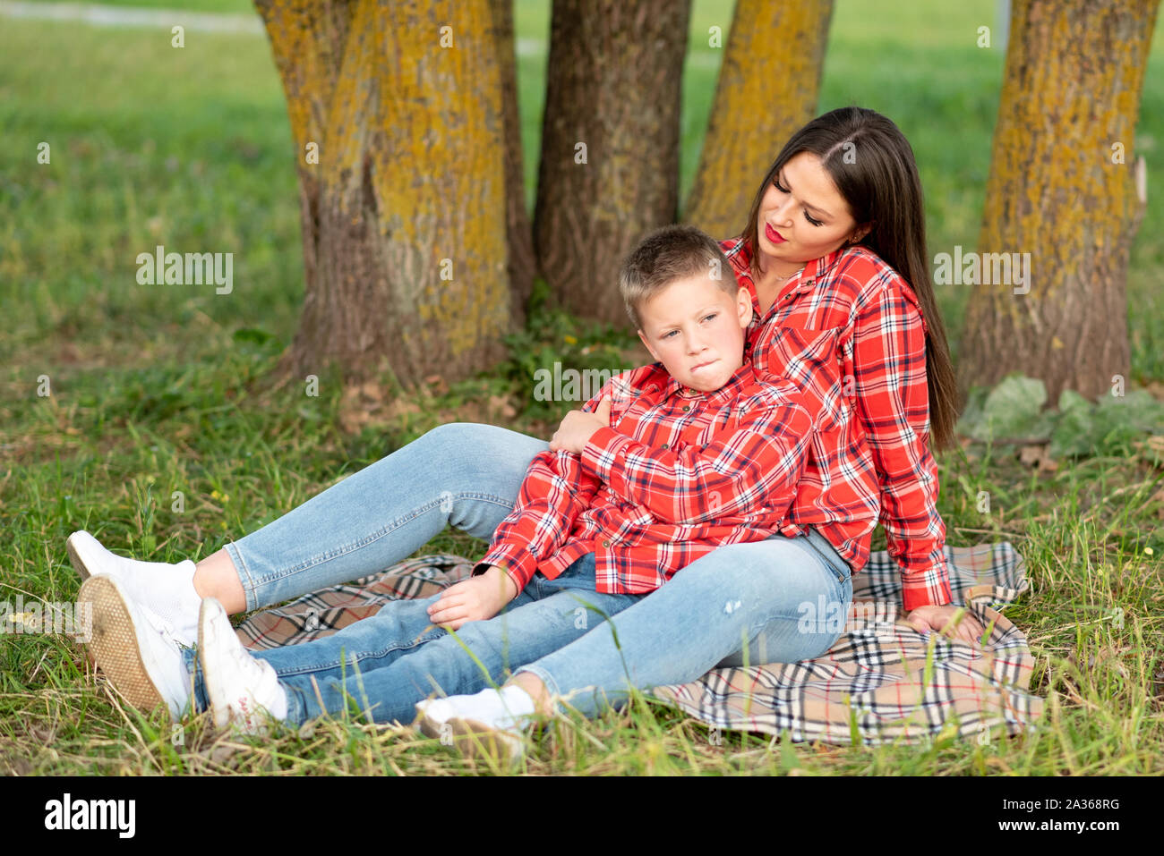 Mom and son, reclining on the bedspread, the son frowns, purses his