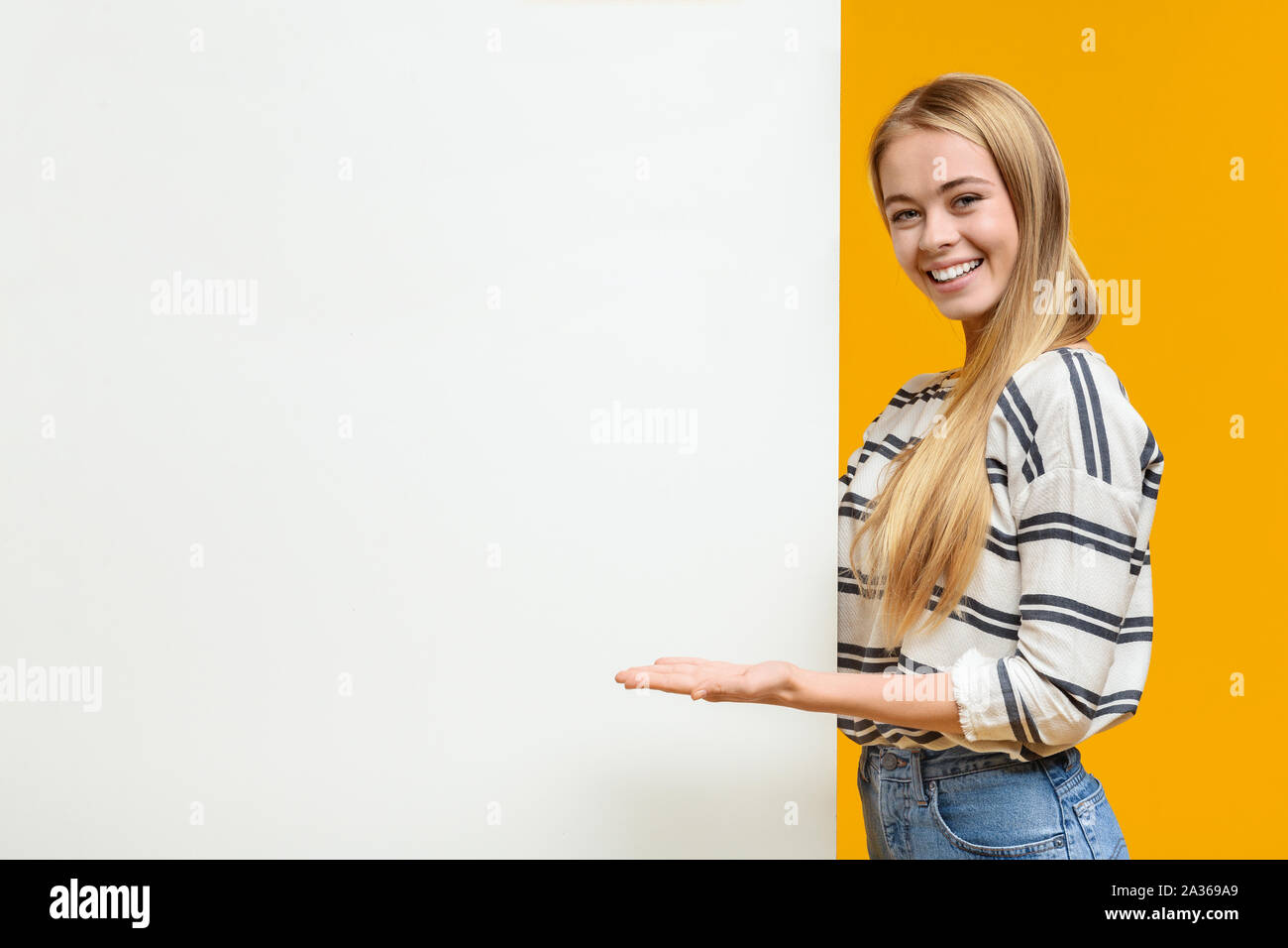 Beautiful girl pointing at white blank placard with open palm Stock Photo