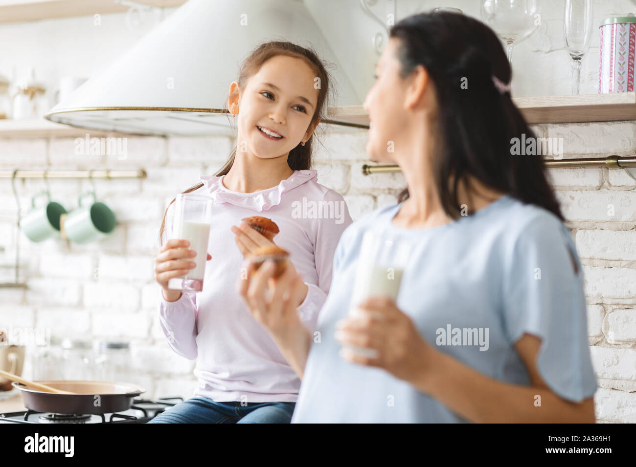 Happy mother and daughter having a bite in kitchen together Stock Photo