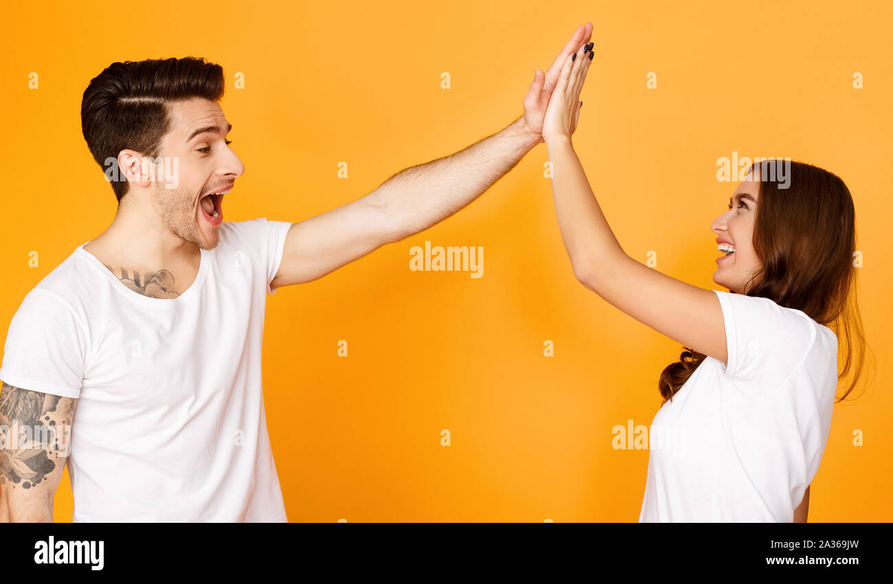 Joyful man and woman greeting each other with high five Stock Photo