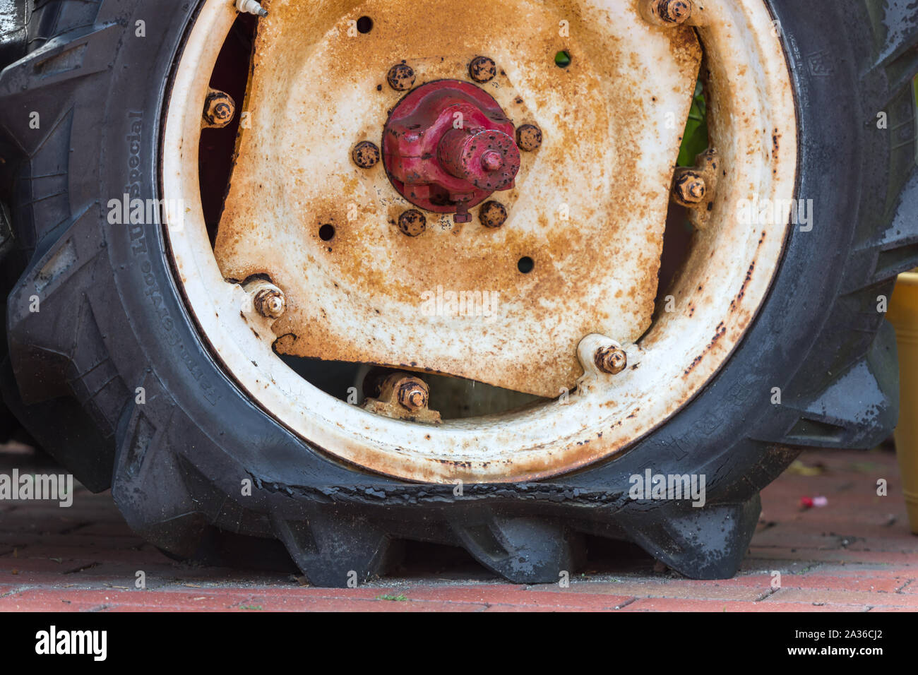 Old rusty tractor's flat back tire. Stock Photo