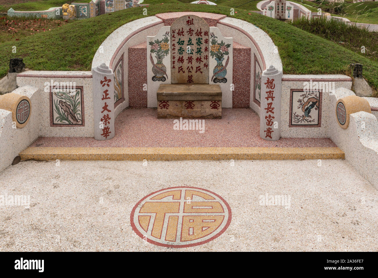 Bang Phra, Thailand - March 16, 2019: Chao Pho Khao Chalak Chinese Cemetery. Fish, flowers and synbol as decoration of beige-red family grave tombston Stock Photo