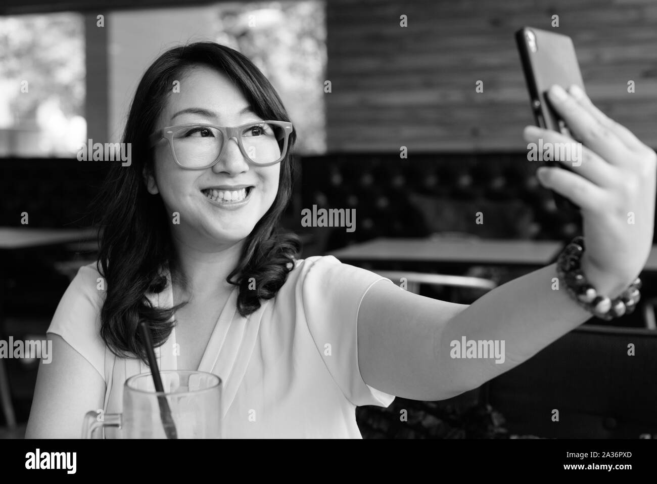 Happy Asian woman relaxing at coffee shop and taking selfie Stock Photo ...