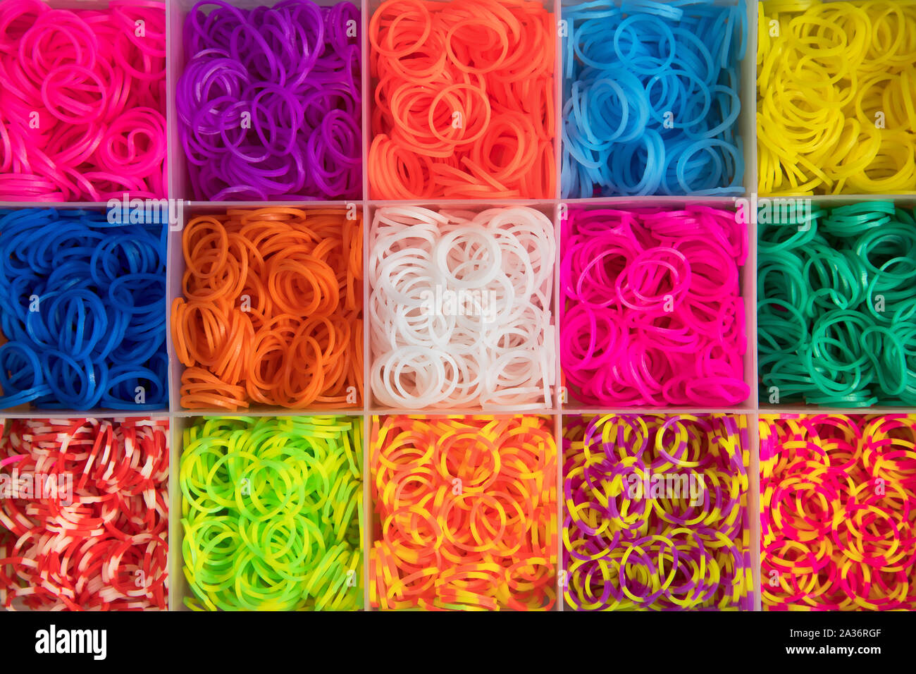 Colourful background texture of multicolored elastic bands arranged in square compartments in a box viewed from overhead in full frame Stock Photo