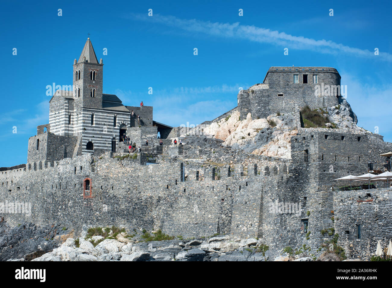 View of the historic Gothic Church of Saint Peter, Portovenere, Italy which faces out over the Gulf of Poets viewed from below against a blue sky Stock Photo