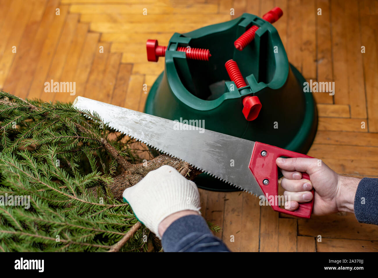 Gloved hands using a saw to cut branches at the bottom of the