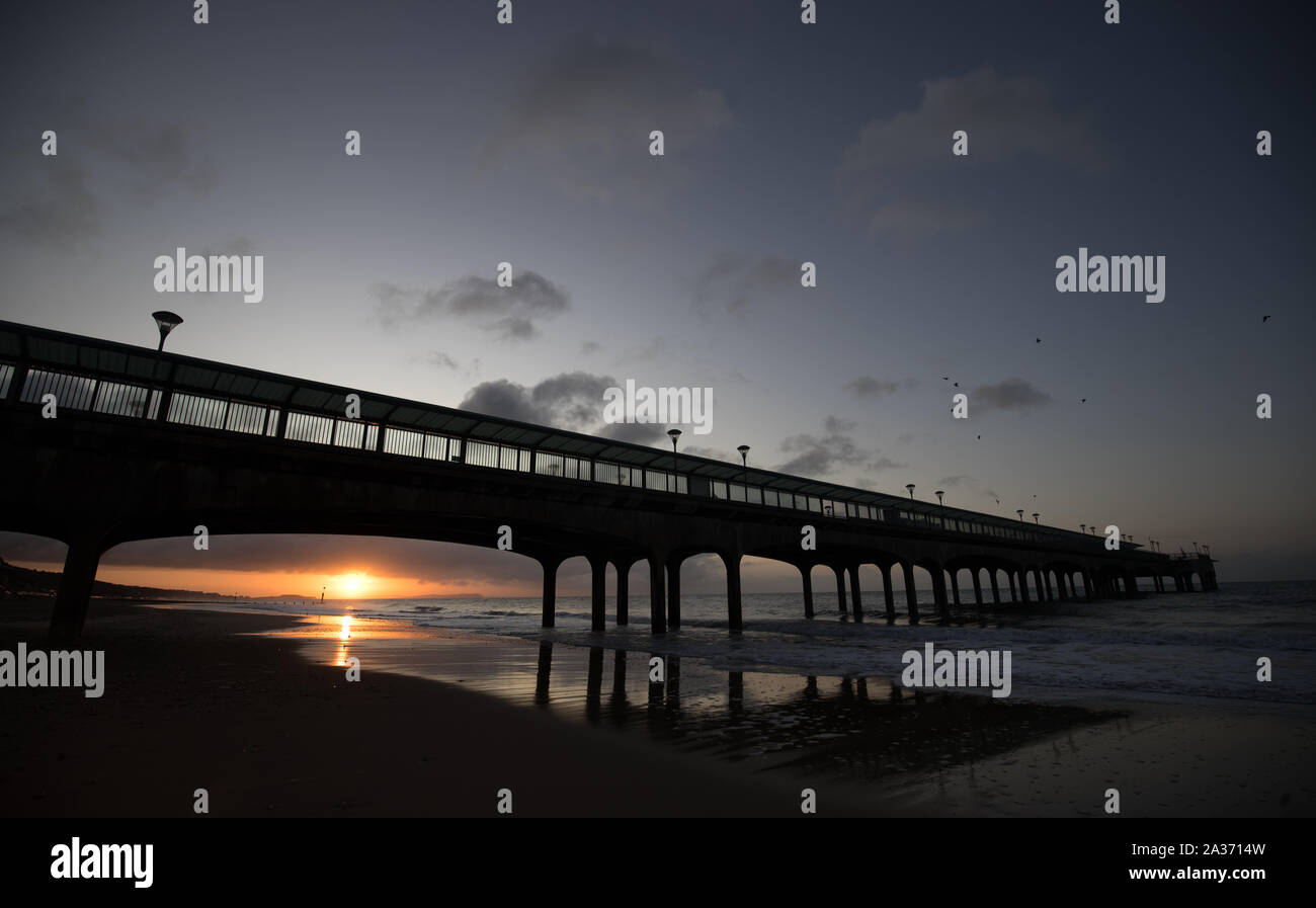 The sun rises behind Boscombe pier in Dorset. Heavy rain is due to hit a large swathe of the UK just days after the country was struck by extensive flooding. Stock Photo