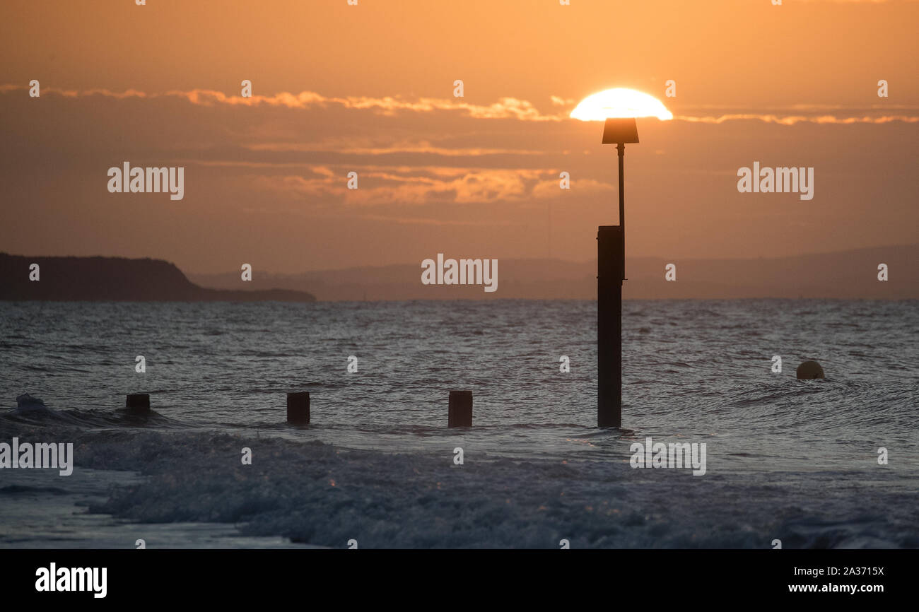 The sun rises over Boscombe beach in Dorset. Heavy rain is due to hit a large swathe of the UK just days after the country was struck by extensive flooding. Stock Photo