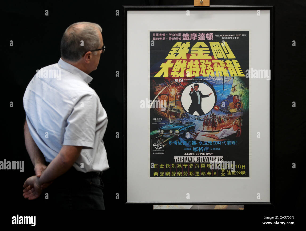Embargoed to 0001 Monday October 07 Prop Store poster consultant Mike Bloomfield looks at a Carlsberg Poster for the 1987 James Bond film The Living Daylights (estimate £100-200) during a preview for the Prop Store's forthcoming cinema poster live auction. Stock Photo