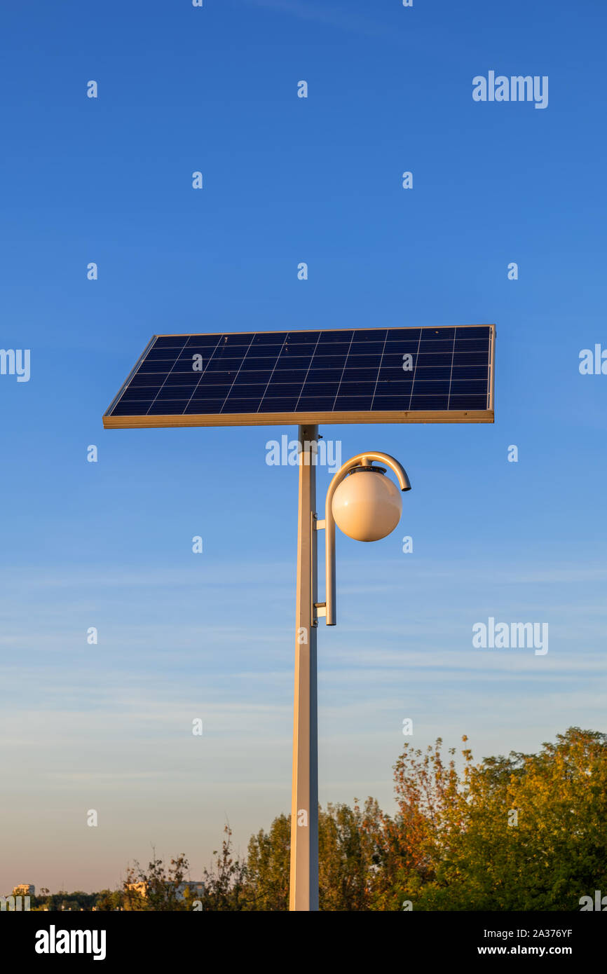 Park lamp powered by solar panel, sustainable, renewable green energy source from photovoltaic module. Stock Photo