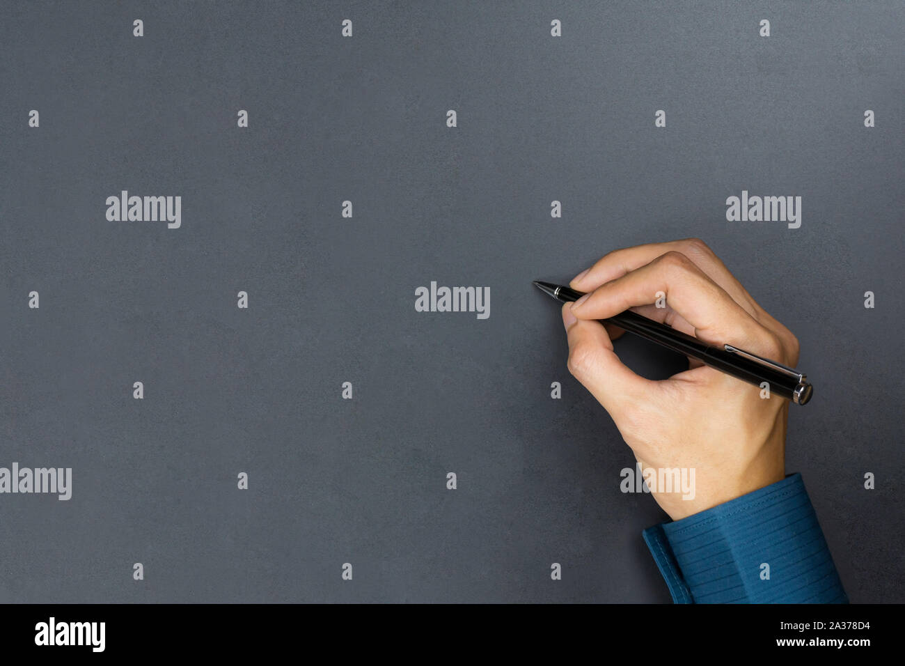 A businessman hand holding black pen and write something on chalkboard. Stock Photo