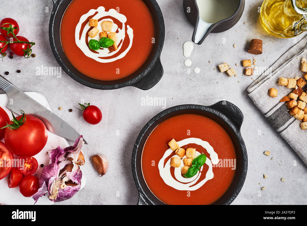 Tomato soup with cream, croutons and basil in a black bowl on stone background. Top view. Copy space for text. Stock Photo
