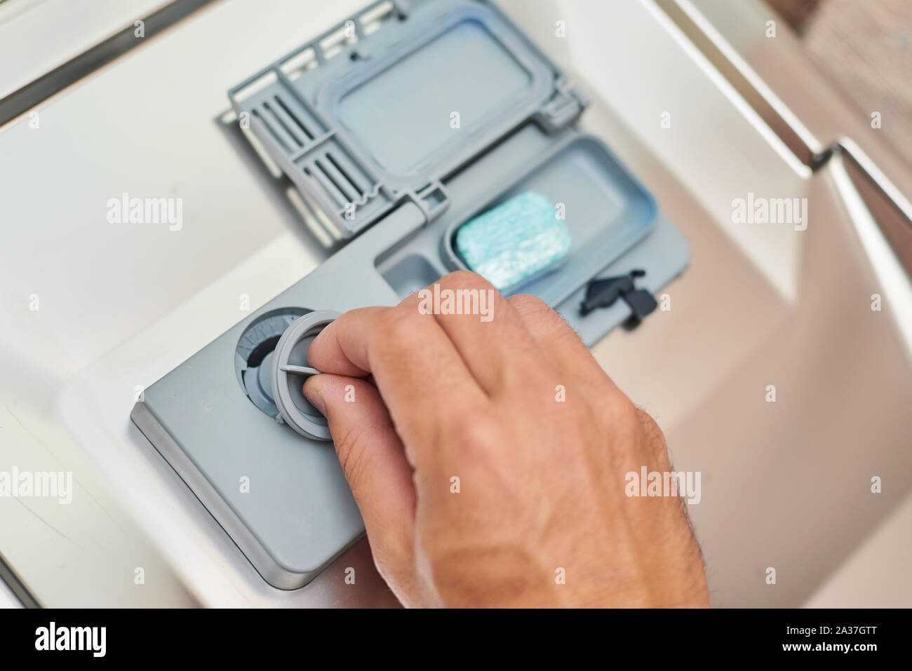 Hand putting soap tablet in dishwasher machine, close up. Kitchen