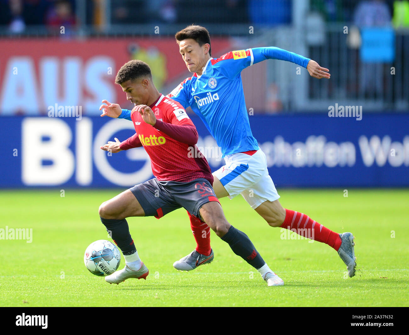 Kiel, Germany. 06th Oct, 2019. Soccer: 2nd Bundesliga, Matchday 9: Holstein Kiel - Jahn Regensburg in Holstein Stadium. Regensburg's Chima Okoroji (l) and Kiel's Jae-Sung Lee fight for the ball. Credit: Daniel Bockwoldt/dpa - IMPORTANT NOTE: In accordance with the requirements of the DFL Deutsche Fußball Liga or the DFB Deutscher Fußball-Bund, it is prohibited to use or have used photographs taken in the stadium and/or the match in the form of sequence images and/or video-like photo sequences./dpa/Alamy Live News Stock Photo