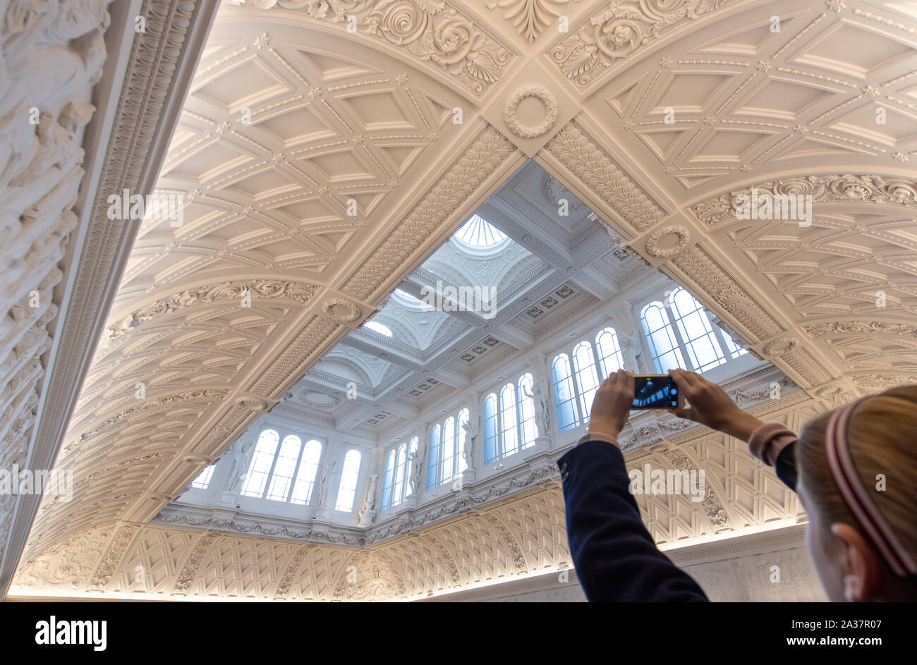 A person takes a photo of the newly refurbished Grade 1 listed ceiling in the main gallery at the Fitzwilliam Museum in Cambridge, featuring ornate plasterwork and casts of the Parthenon Frieze, widely considered to be one of the finest museum interiors in the world. Stock Photo