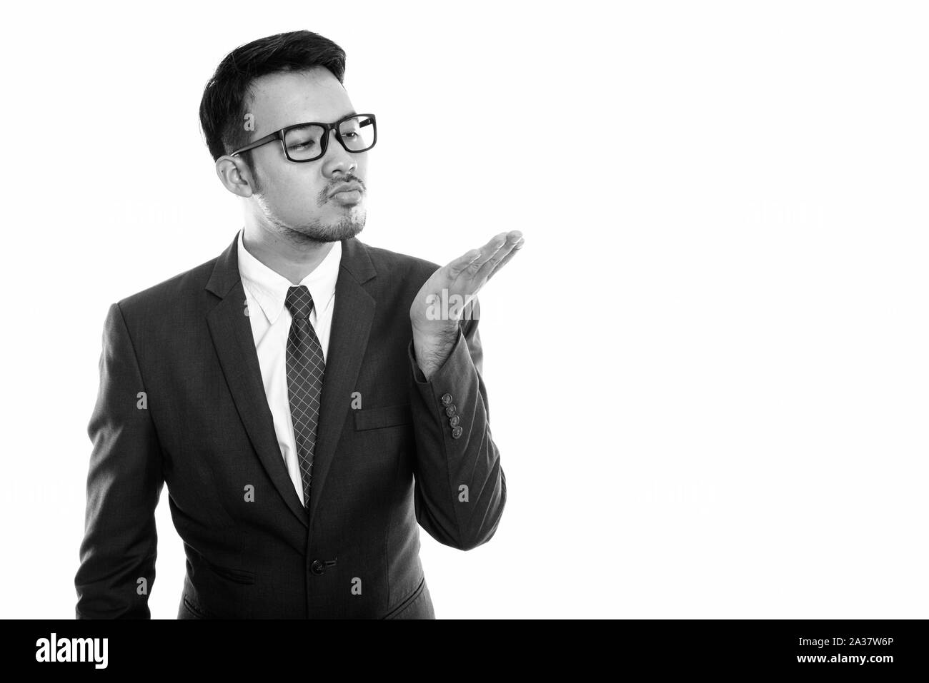 Studio shot of young Asian businessman giving flying kiss Stock Photo