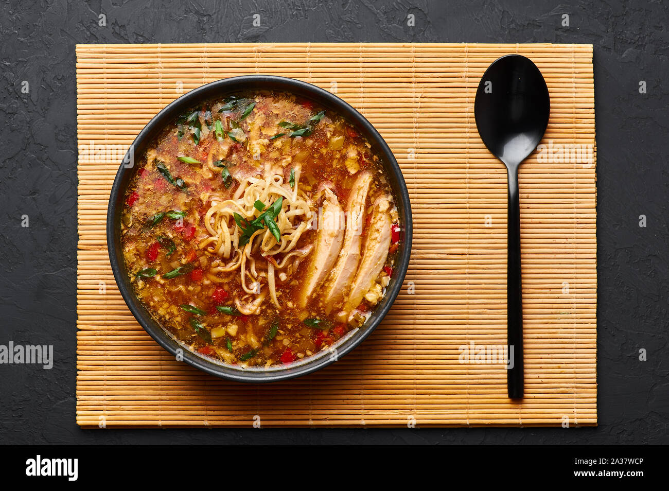 Chicken Manchow Soup in black bowl at dark slate background. Chicken