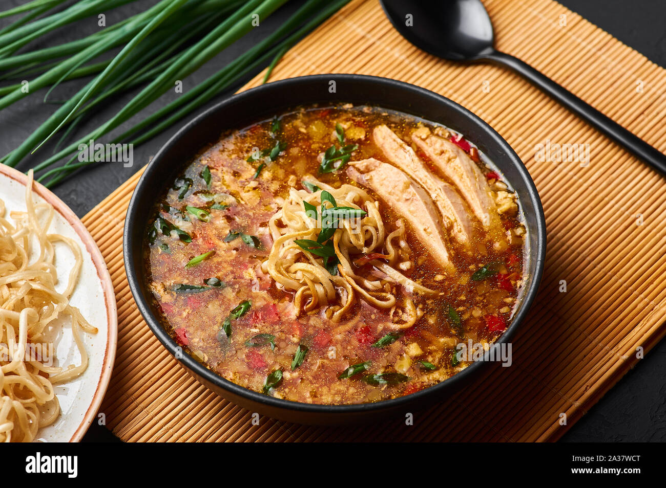 Chicken Manchow Soup in black bowl at dark slate background. Chicken