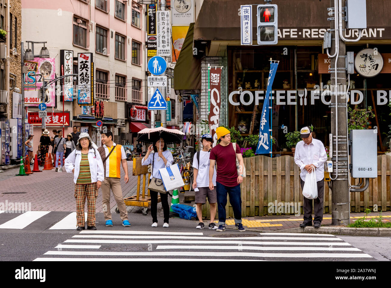 Japanese people ages 20s to 70s waiting at a crosswalk on a red light in Tokyo, Japan Stock Photo